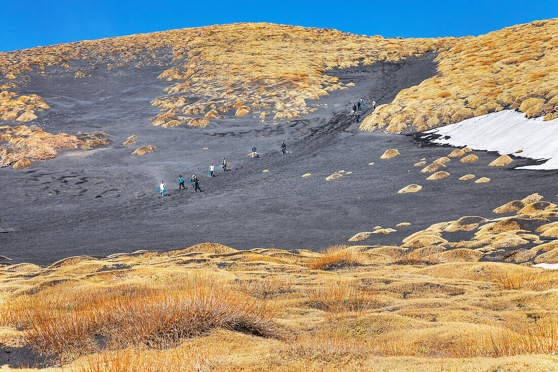 Group of hikers walking down Valle del Bove, Etna, Sicily, Italy