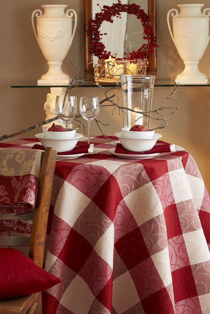 An autumnal table laid with a checked cloth, pomegranates and a lantern