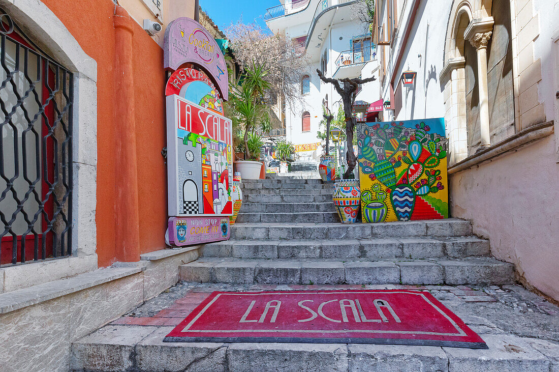  Altstadtstraße voller Werbetafeln und Kunstwerke, Taormina, Sizilien, Italien 