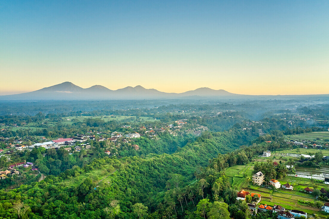  Luftaufnahme der Stadt Ubud in der Nähe des Campuhan Ridge Walk mit Berggipfeln im Hintergrund. Bali, Indonesien. 