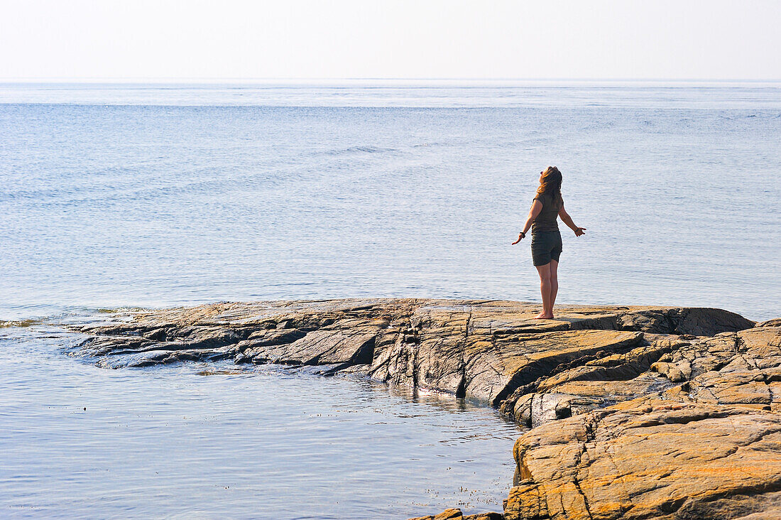 woman standing on rock at the confluence of Saguenay and Saint Lawrence rivers,Tadoussac,Cote-Nord region,Province of Quebec,Canada,North America