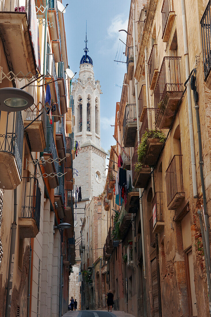 The bell tower of the Church of Sant Joan as seen from a narrow street in the old quarter of Valls town, Catalonia, Spain.