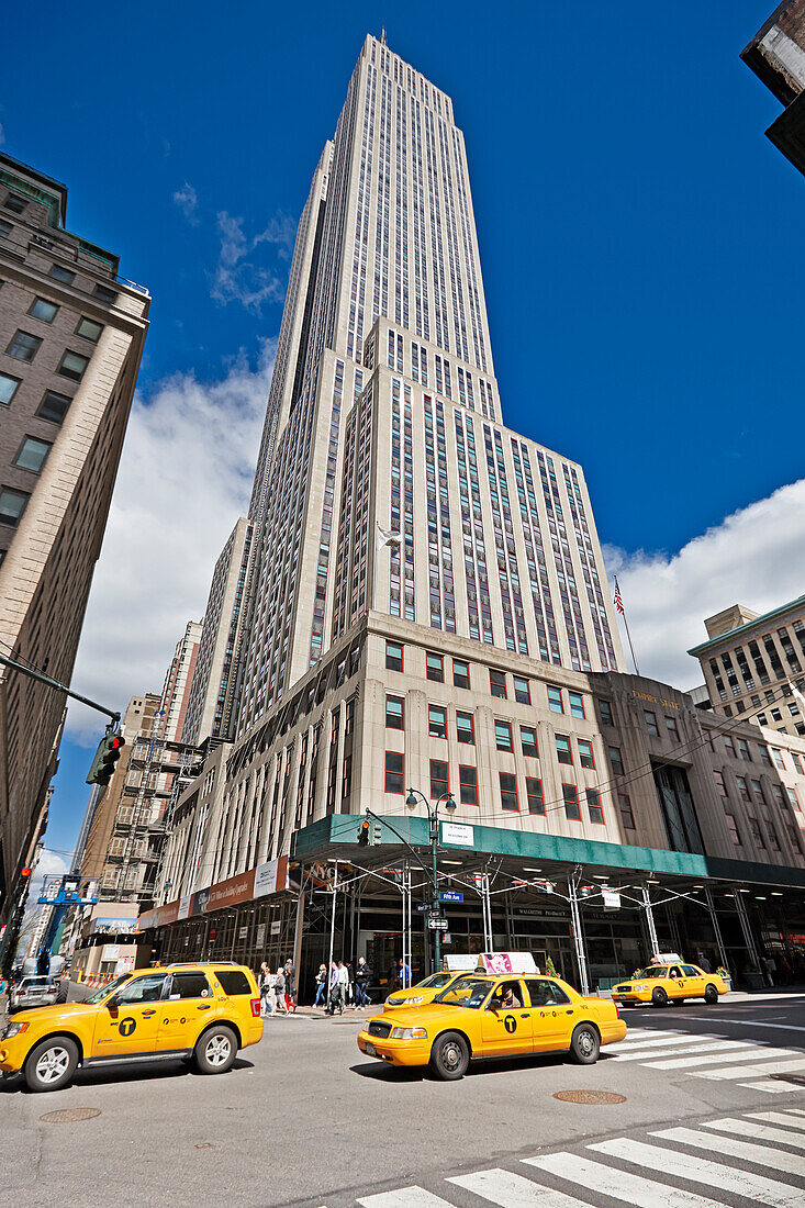 Gelbe Medaillon-Taxis fahren am Empire State Building vorbei. Manhattan, New York City, USA.