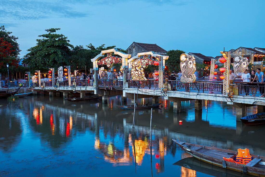 View of the Cau An Hoi Bridge illuminated at dusk and reflected in Thu Bon River. Hoi An Ancient Town, Quang Nam Province, Vietnam.