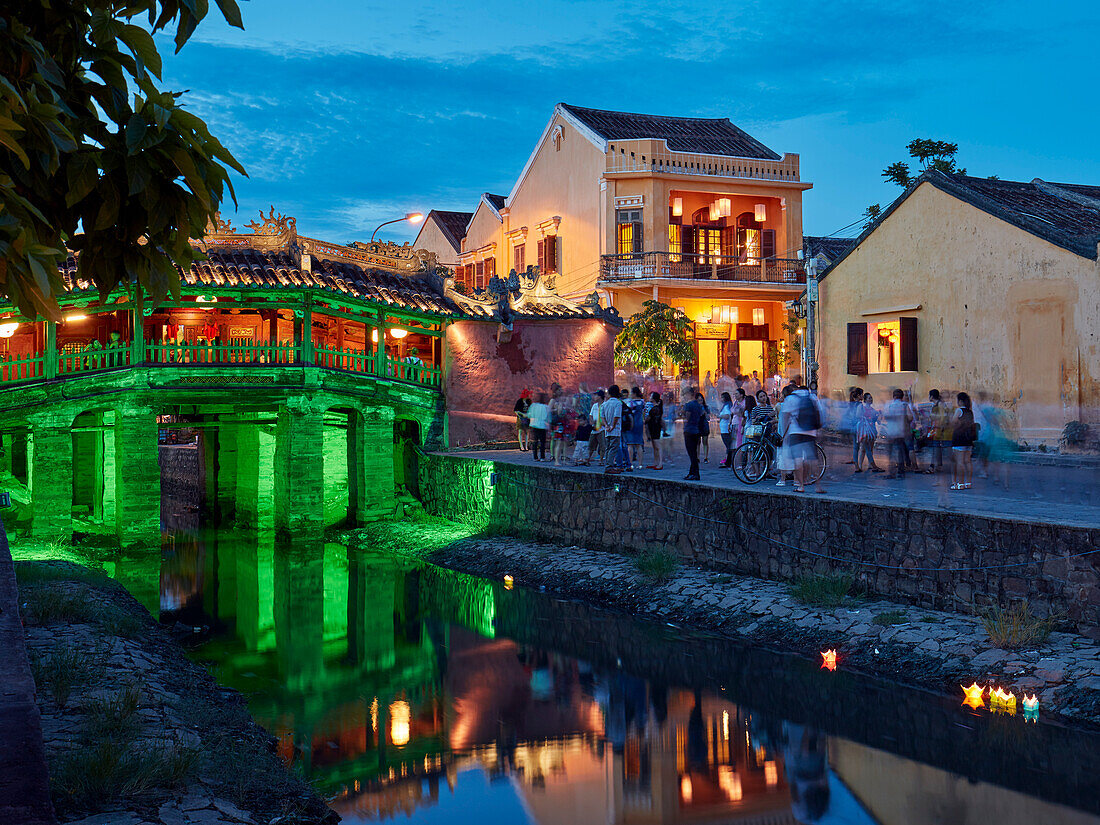  Menschen stehen an der in der Abenddämmerung beleuchteten Japanischen Brücke. Antike Stadt Hoi An, Provinz Quang Nam, Vietnam. 