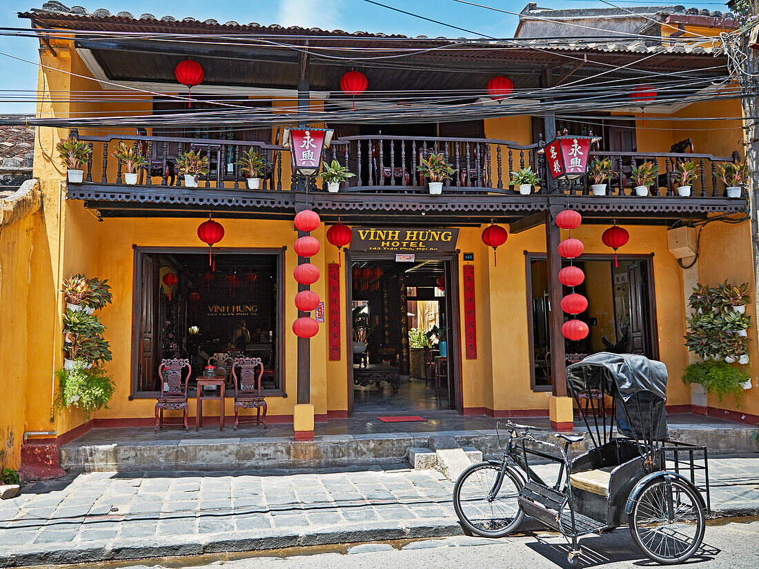  Eine alte Fahrradrikscha parkt vor dem Vinh Hung Hotel in der Altstadt von Hoi An. Hoi An, Provinz Quang Nam, Vietnam. 