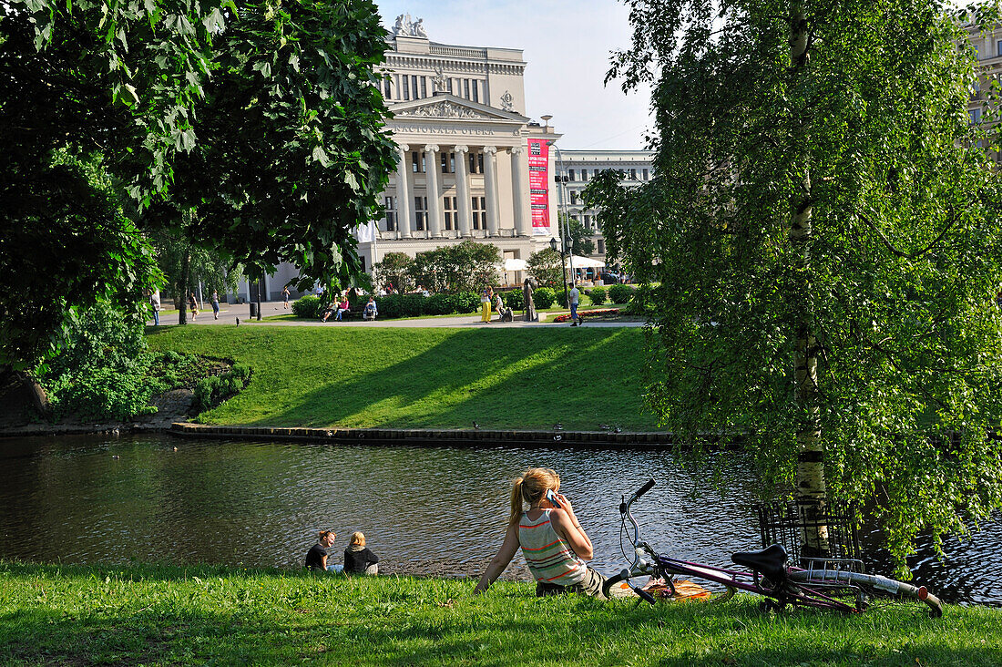 young people on the bank of the Canal surrounding the Old Town of Riga,in front of the National Opera house,Latvia,Baltic region,Northern Europe