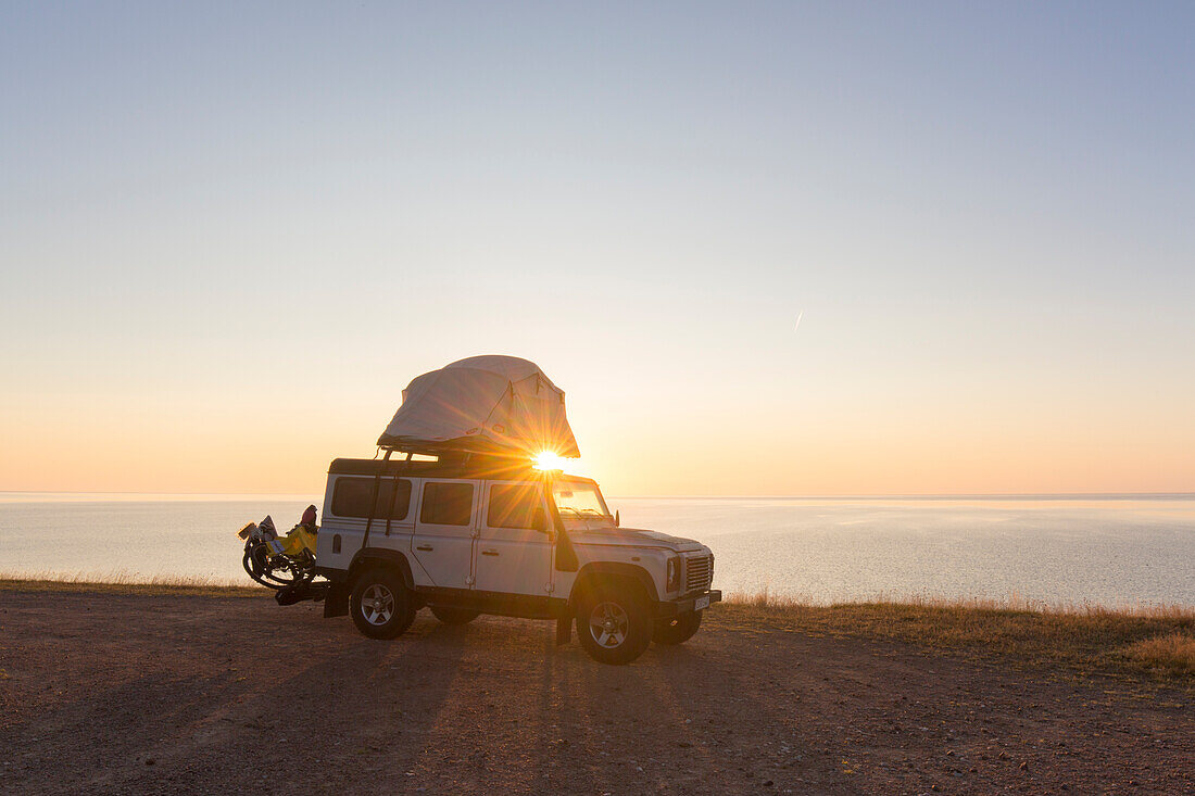  Off-road vehicle with roof tent camping at the Baltic Sea at sunrise, summer, Scania Province, Sweden 