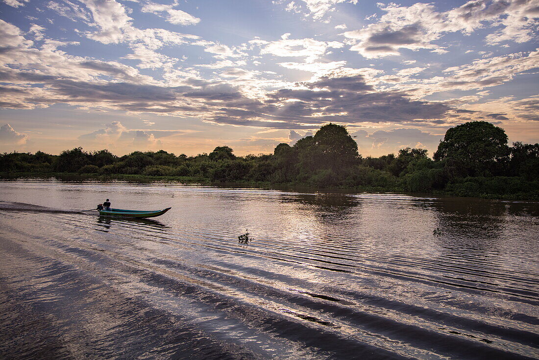  Silhouette of a longtail boat on canal at Tonle Sap Lake at sunset, Chong Khnies, near Siem Reap, Siem Reap Province, Cambodia, Asia 