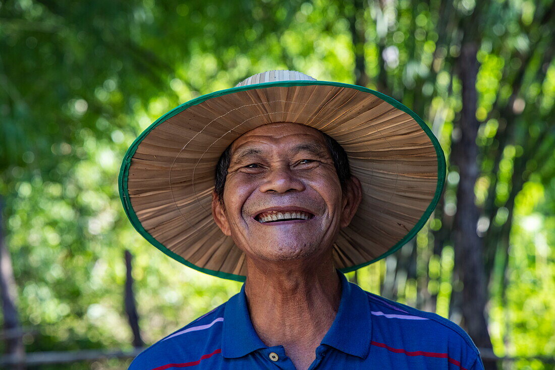  Portrait of a cheerful Cambodian man with a big smile and a sun hat, Srae Thmei, Role Bier District, Kampong Chhnang, Cambodia, Asia 