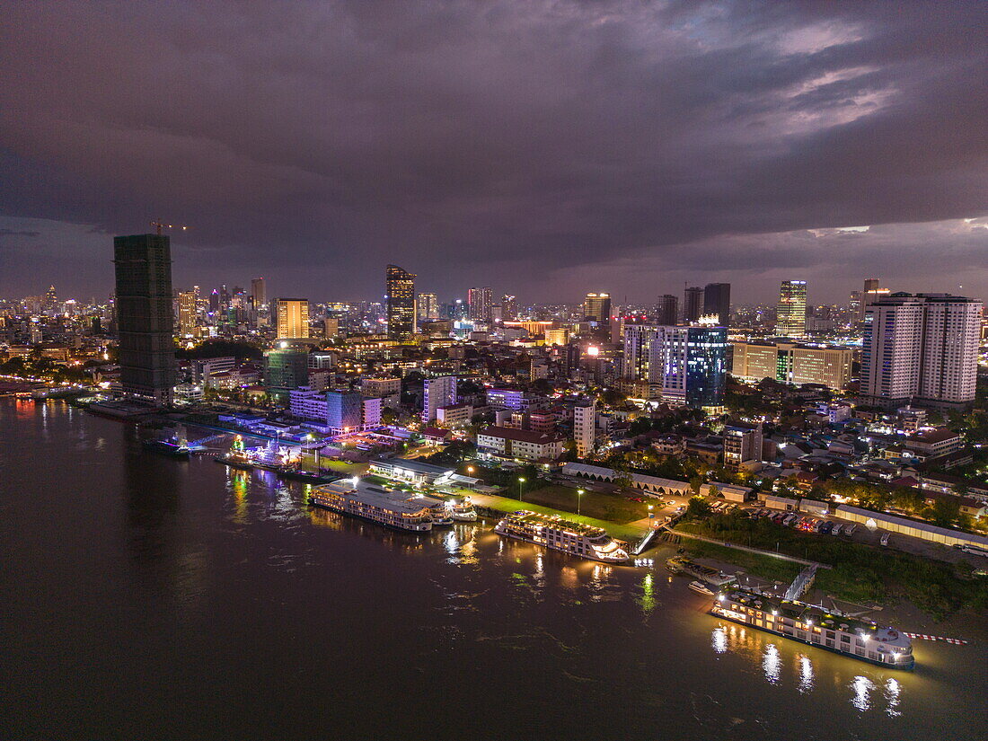 Luftaufnahme von Flusskreuzfahrtschiffen am Tonle Sap-Fluss, mit der Skyline in der Abenddämmerung, Daun Penh District, Phnom Penh, Kambodscha, Asien