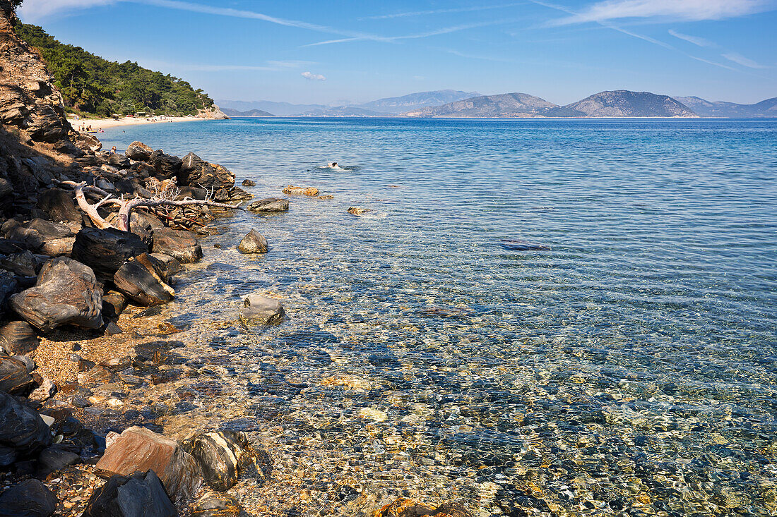 A rocky beach with crystal clear turquoise sea water at Dilek Peninsula National Park, Aydin Province, Turkey.