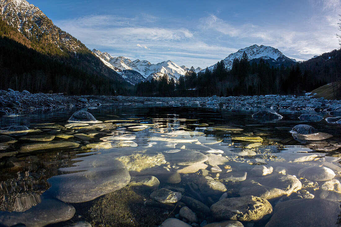  River landscape Stillach valley with snow-covered mountain panorama, stone riverbed, mountain river Stillach, Alps, Oberallgäu, Bavaria, Germany\n 