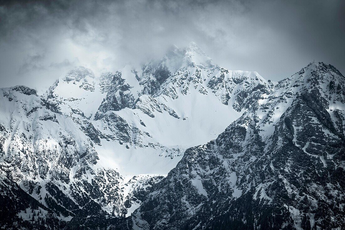  Mountain landscape, massive rock face, stone wall in winter, rock massif, mountain wall, mountain massif, bad weather front with gaps in the sun, Oberallgäu, Alps, Bavaria, Germany\n 