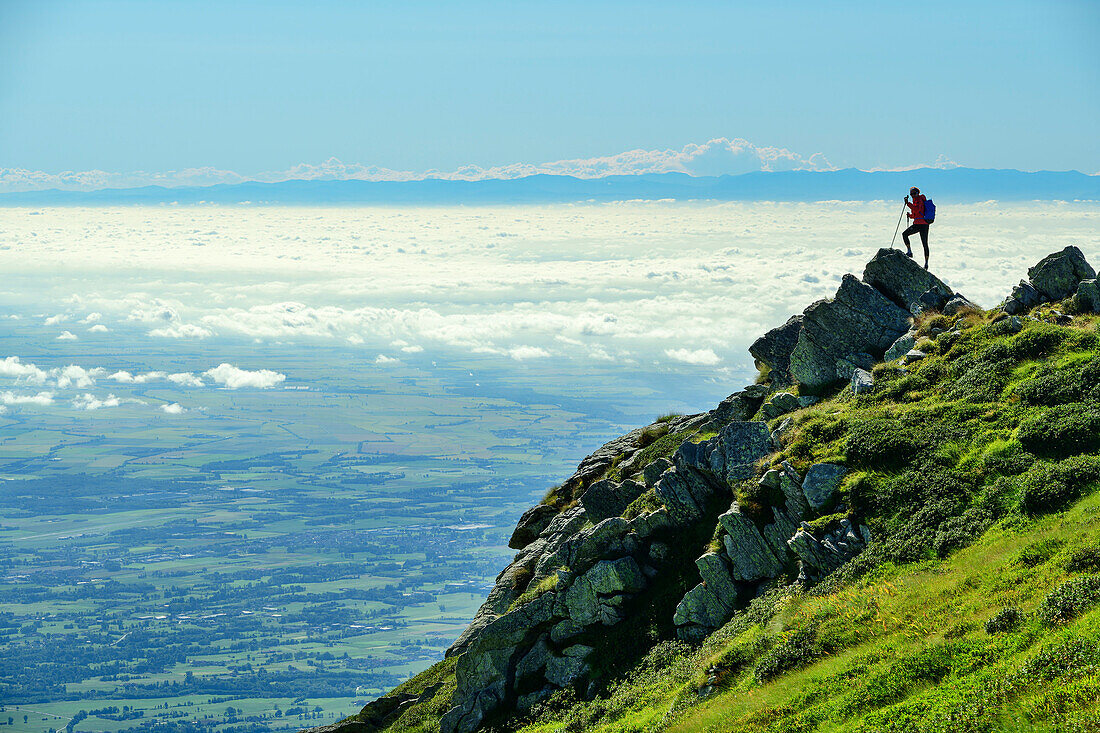  Woman mountaineering standing on rocks and looking at sea of fog in Italian lowlands, Cottian Alps in the background, Colma di Mombarone, GTA, Grande Traversée des Alpes, Biella, Alpi Biellesi, Valais Alps, Piedmont, Italy 