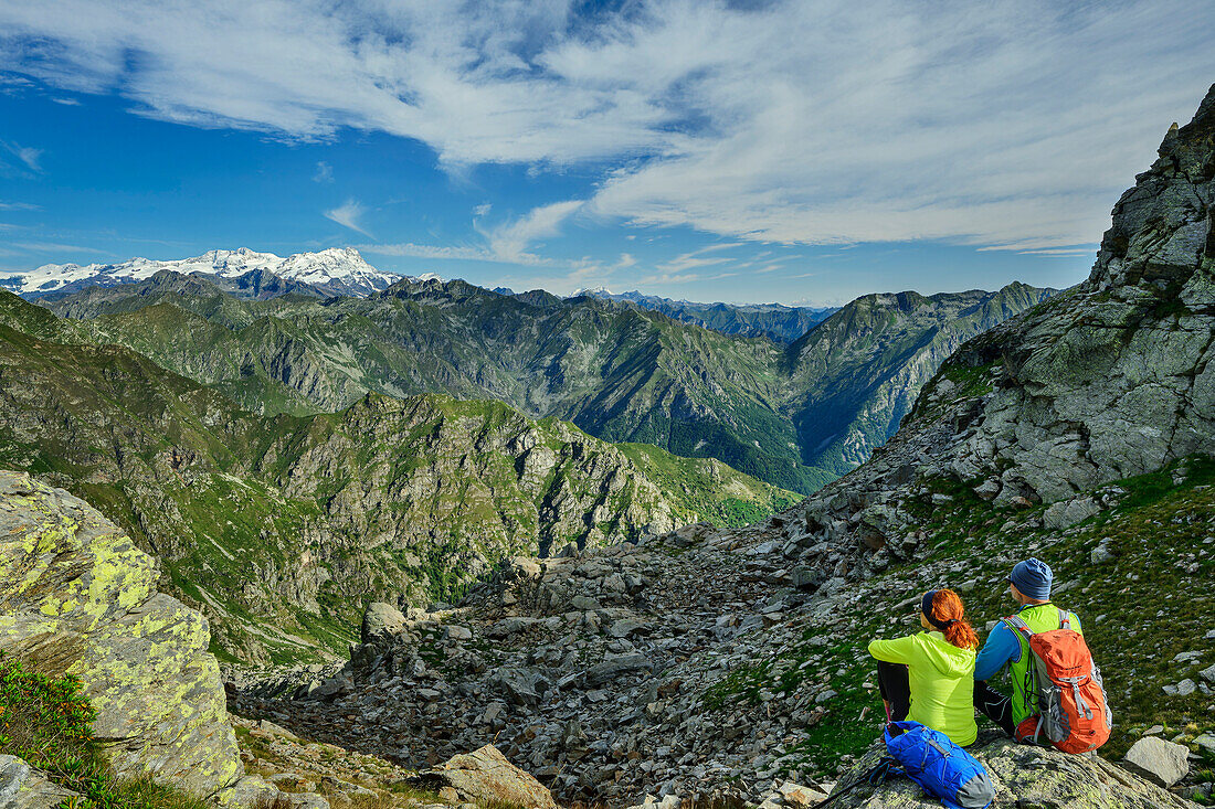  Man and woman hiking sitting on Monte Camino and looking at Monte Rosa and Valais Alps, GTA, Grande Traversée des Alpes, Biella, Alpi Biellesi, Valais Alps, Piedmont, Italy 