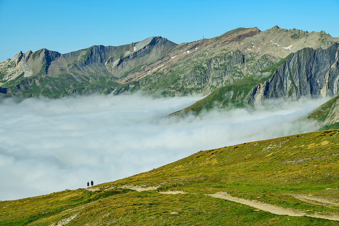  Two people hiking ascend from a sea of fog to the Col de la Seigne, Col de la Seigne, Tour du Mont Blanc, Mont Blanc Group, Graian Alps, Aosta Valley, Italy 