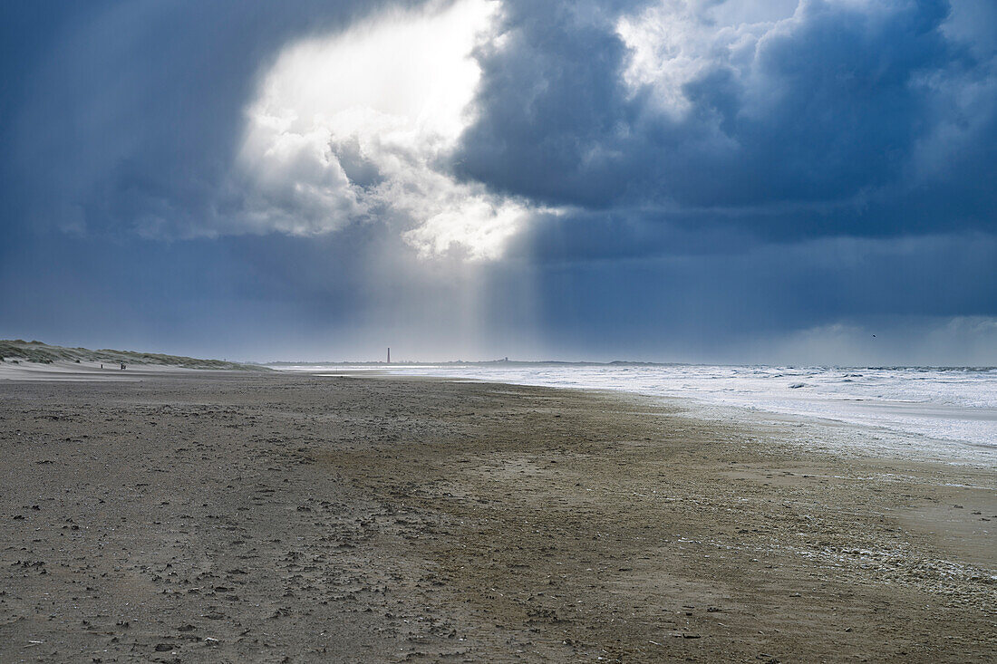 Dunkle Sturmwolken und Sonnenstrahlen am Strand vor dem aufgewühltem Meer, Westfriesische Insel Texel, Nordsee, Provinz Nordholland, Niederlande