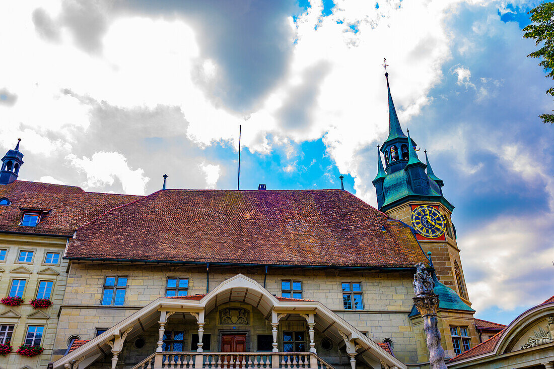  Rathaus mit Uhrturm und Statue an einem sonnigen Sommertag in der Altstadt von Freiburg, Kanton Freiburg, Schweiz. 