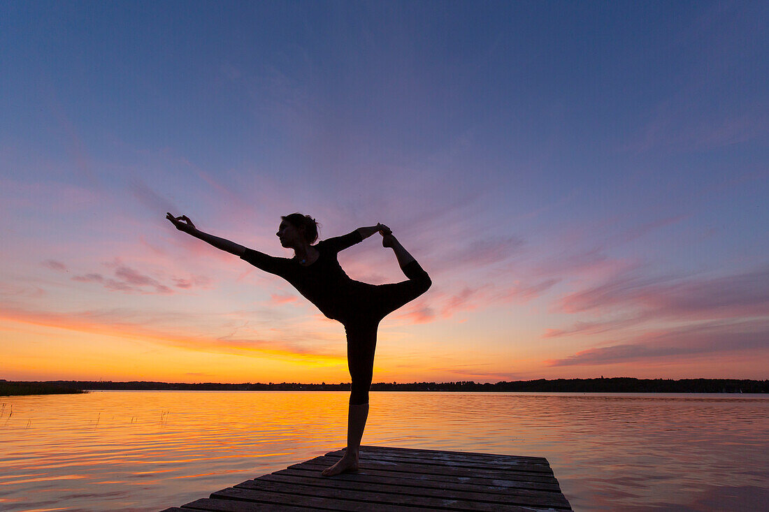  Woman doing yoga exercises on a jetty by the lake, figure dancer, Schleswig-Holstein, Germany 