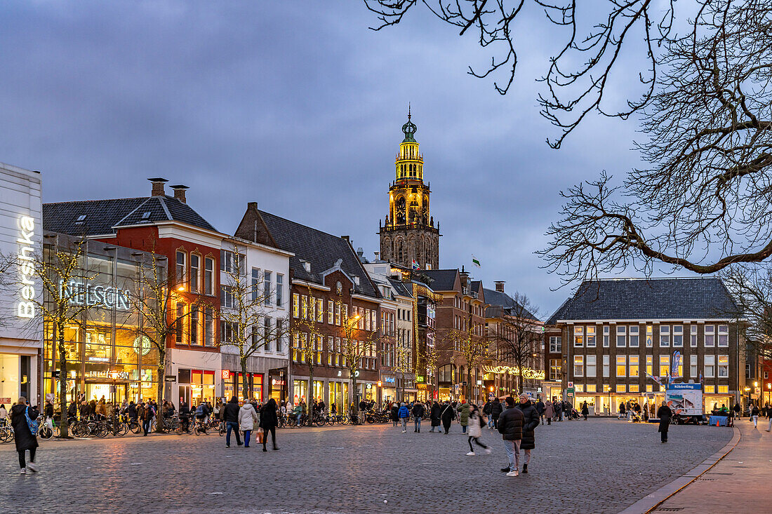  Shops at the fish market Vismarkt and the church tower Martinitoren or Martini Tower of the Martinikerk or Martini Church at dusk, Groningen, Netherlands  