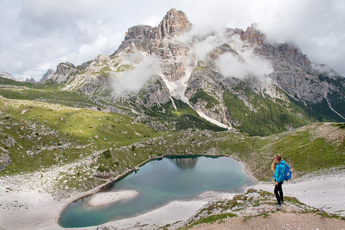 Wanderer auf einem Pfad mit Blick auf den Lago dei Piani inferiore, Naturpark Drei Zinnen, Sextener Dolomiten, Südtirol, Trentino, Italien