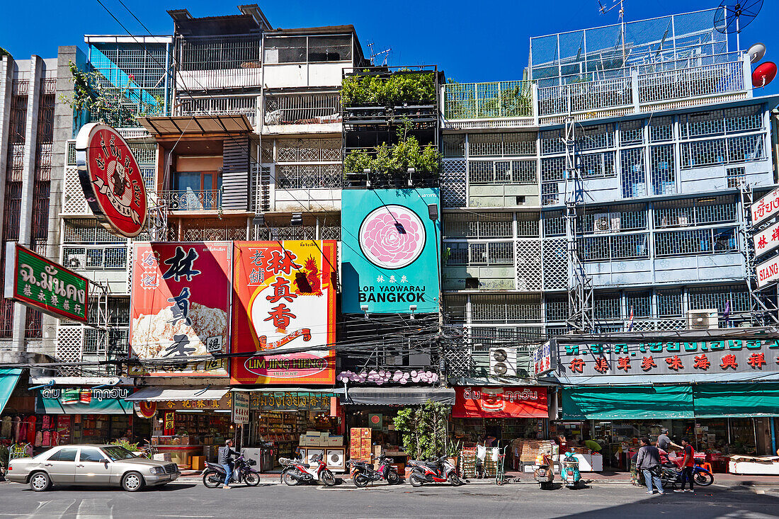 Sunlit colorful advertising billboards on buildings along the Yaowarat Road in Chinatown, Bangkok, Thailand.