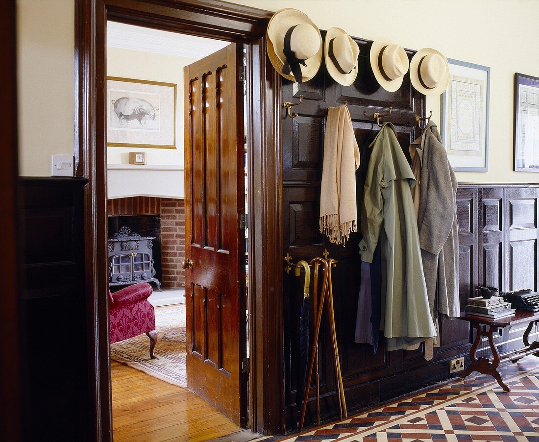 A traditional hallway with a collection of hats on the hooks next to the open living room door
