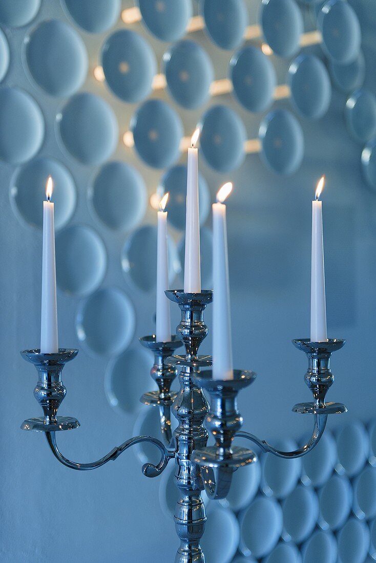 Burning candles in a candle holder against a wall decoration with porcelain, Rosenthal Casino, Selb