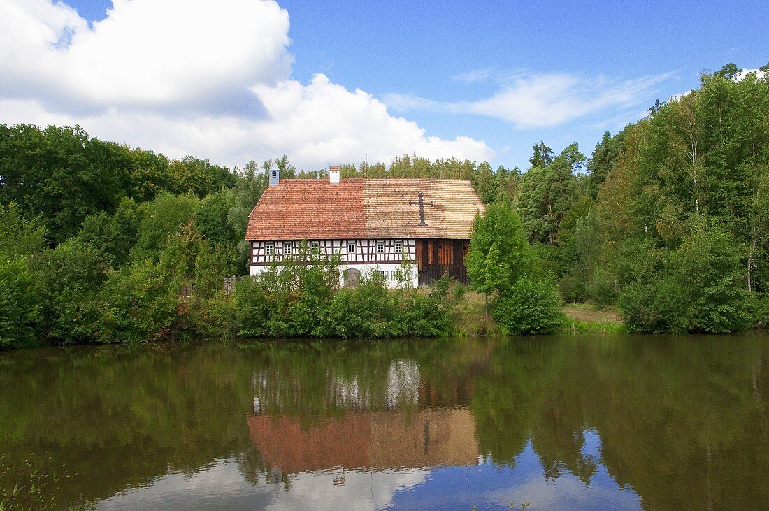 A half-timbered house in a green landscape with a reservoir