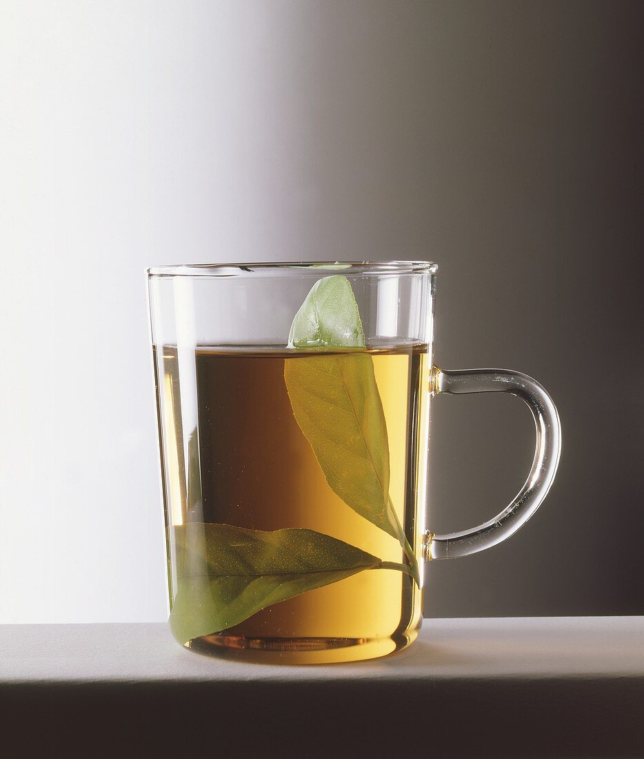 A glass of tea with a fresh bay leaf