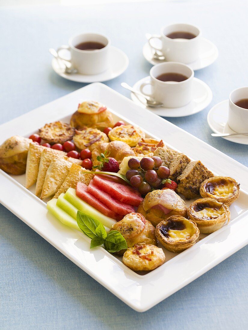 Frühstücks-Platte mit pikamten Gebäck und Obst, Tee