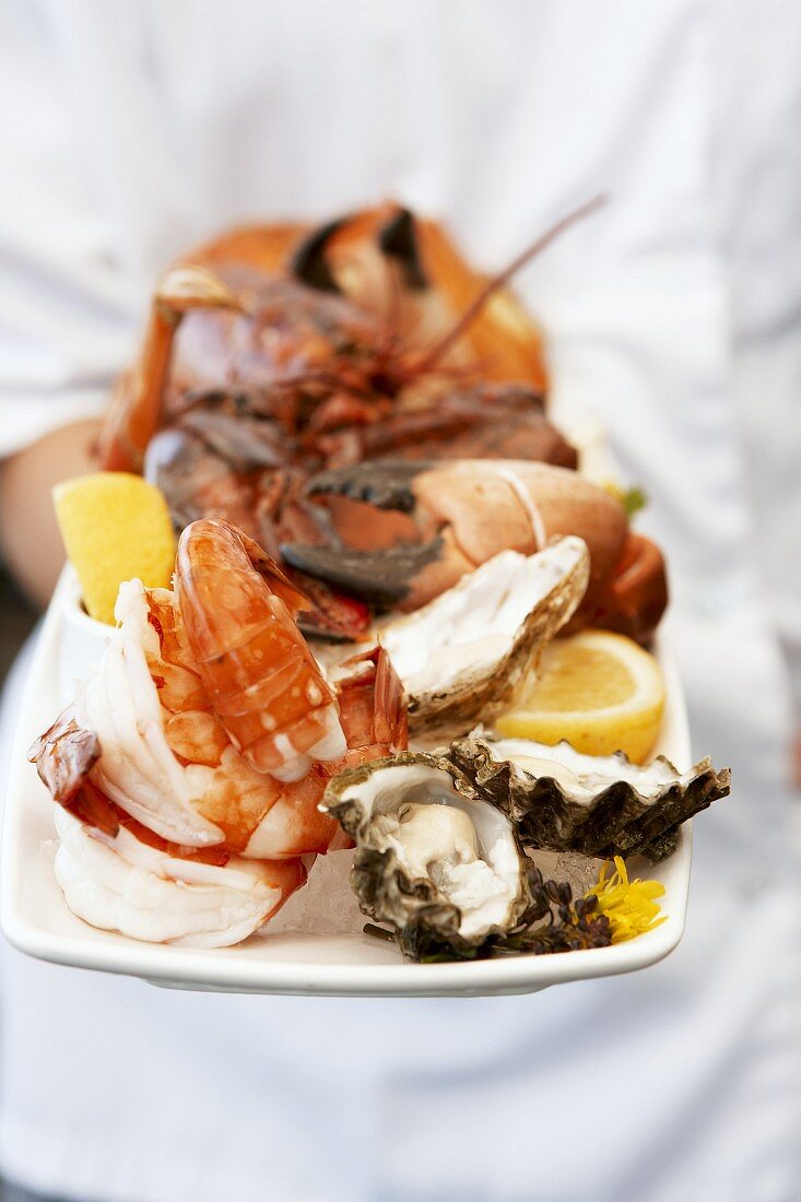 Chef holding platter of assorted seafood