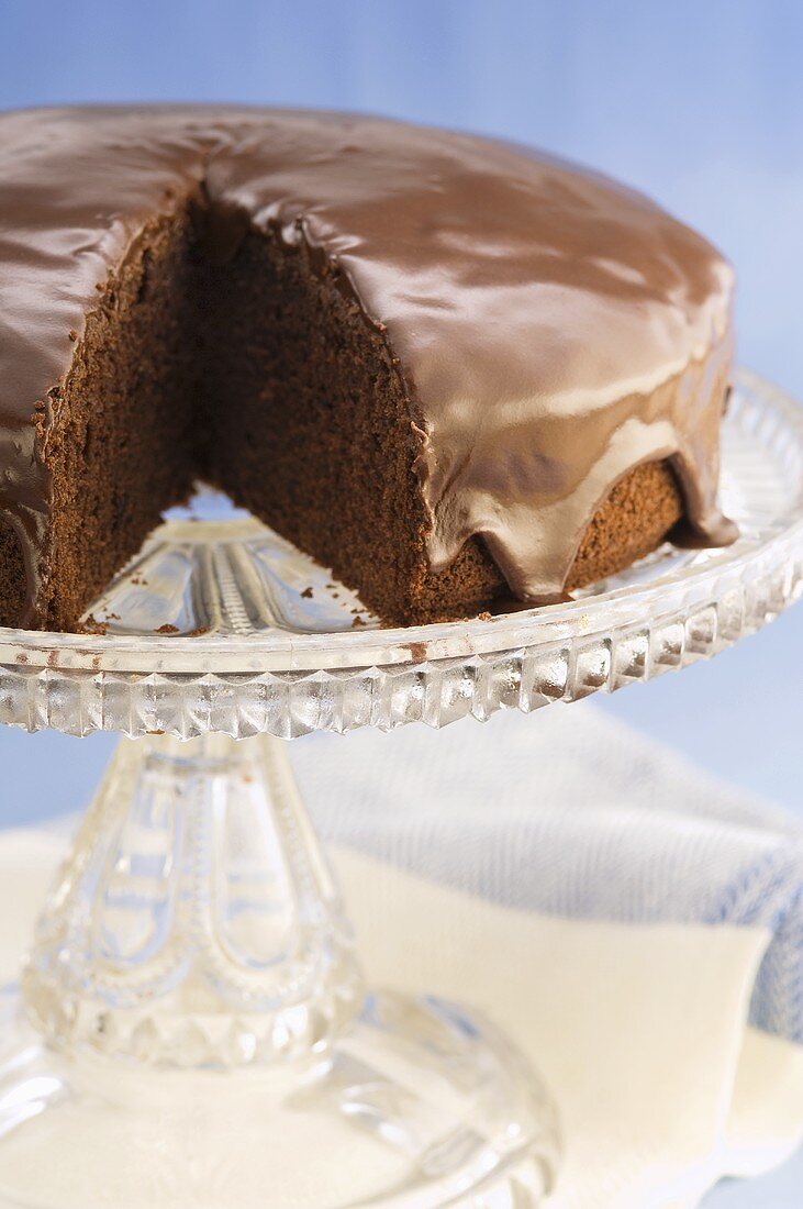 Schokoladentorte mit Schokoglasur auf Kuchenständer (angeschnitten)