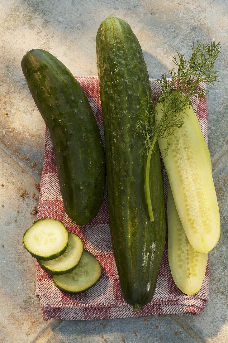 Fresh cucumbers, whole, halved and slices, on tea towel