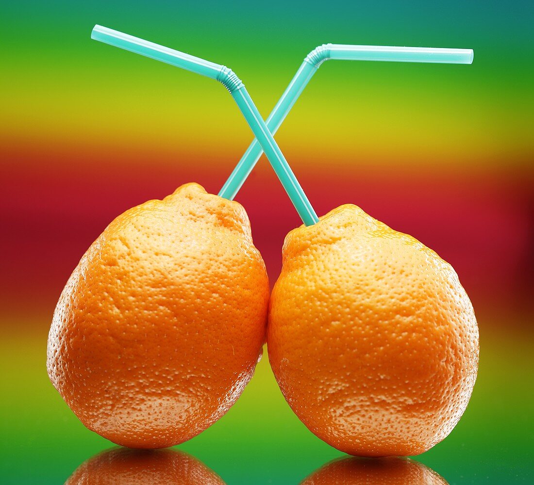 Two tangerines with straws