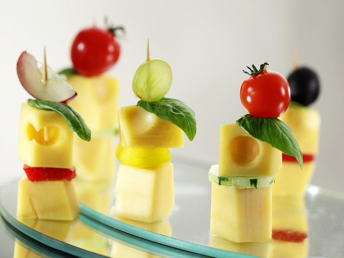 Cubes of cheese on sticks with basil, vegetables and grapes