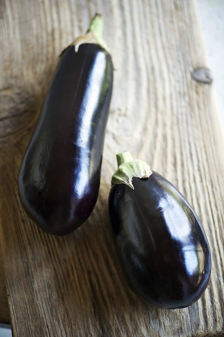 Two aubergines on a wooden board