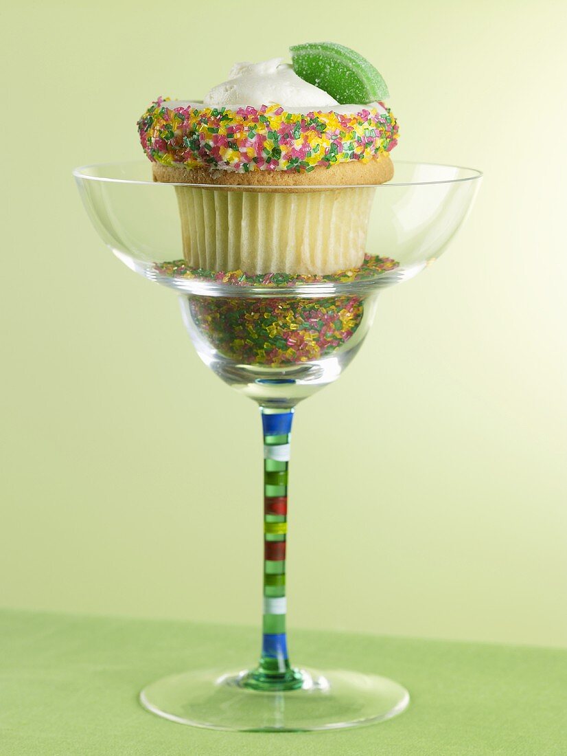 A cupcake decorated with hundreds and thousands in a cocktail glass