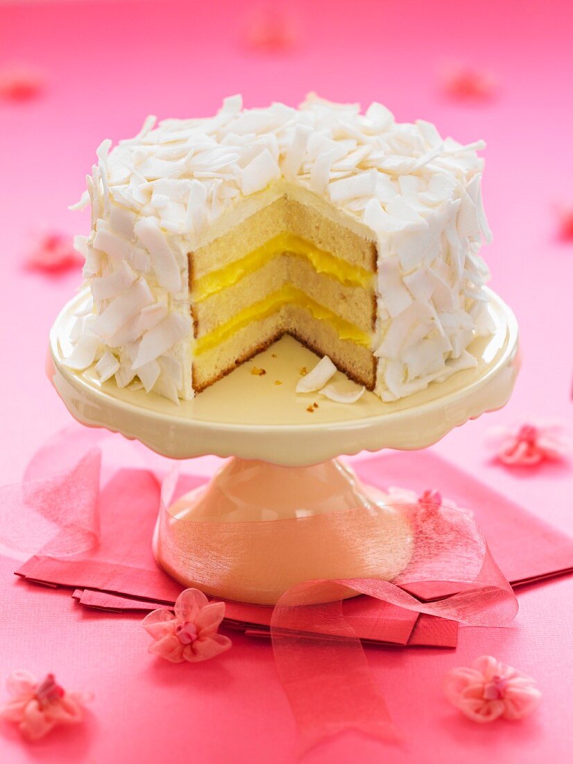 A sliced coconut cake on a cake stand