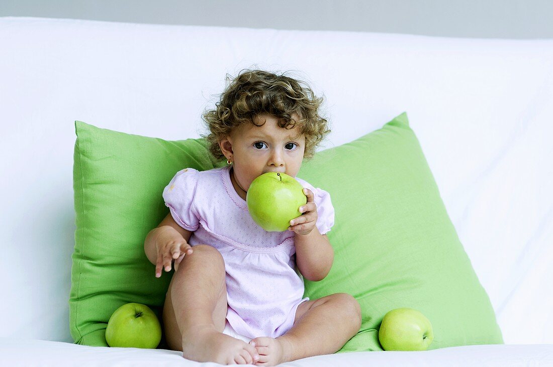 Kleines Mädchen beisst in grünen Apfel