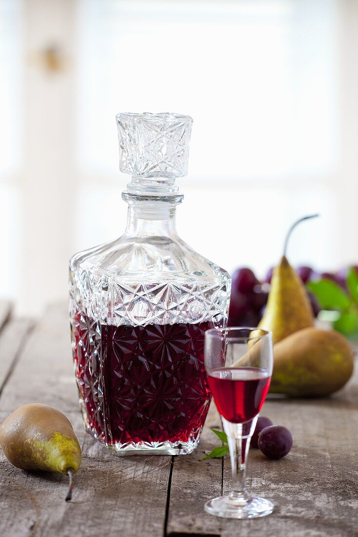 Homemade plum and pear liqueur in a glass and a carafe