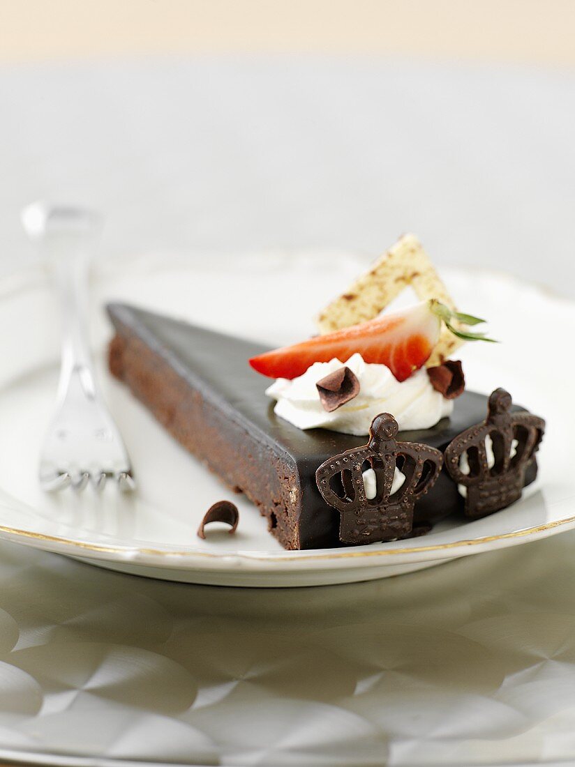 A slice of chocolate cake with cream and strawberries