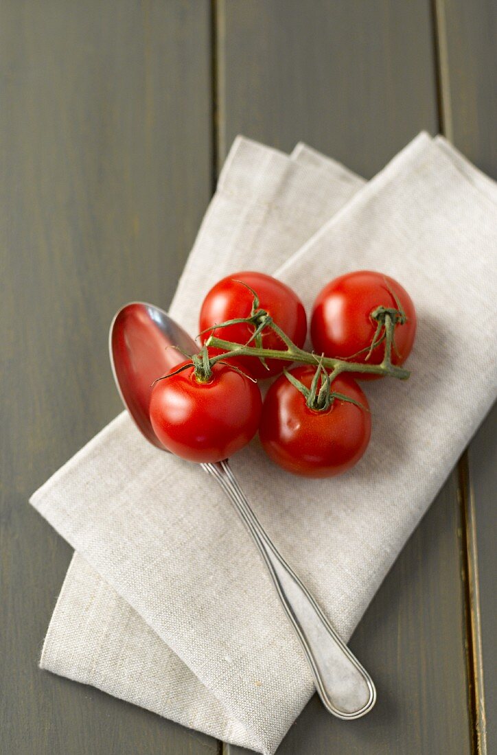 Vine tomatoes and a spoon on a linen cloth