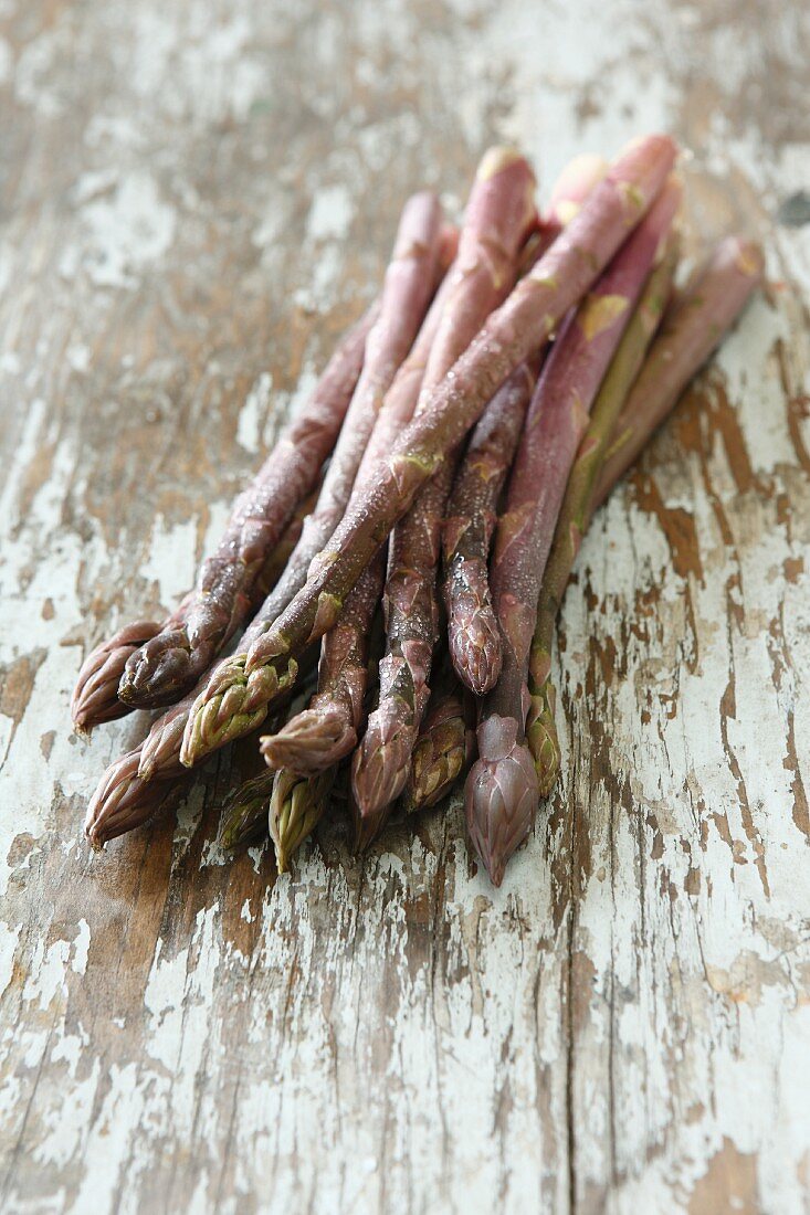 Purple asparagus on a wooden surface