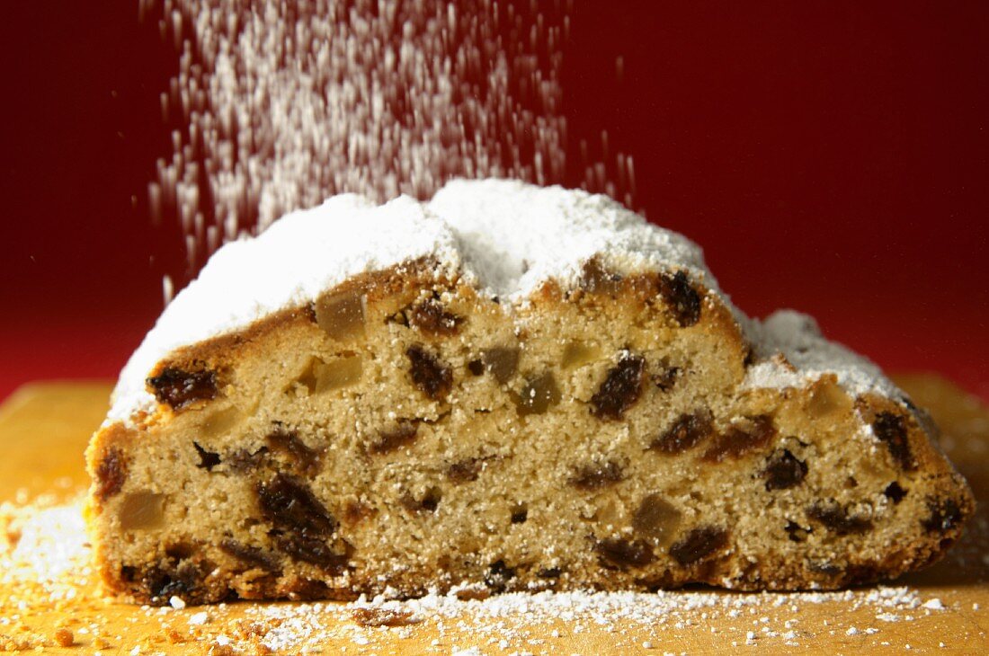 Raisin stollen being dusted with icing sugar