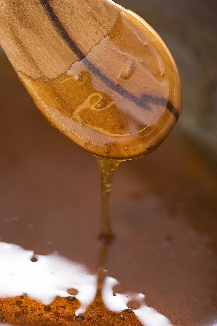 Honey & sugar caramel drizzling from a wooden spoon