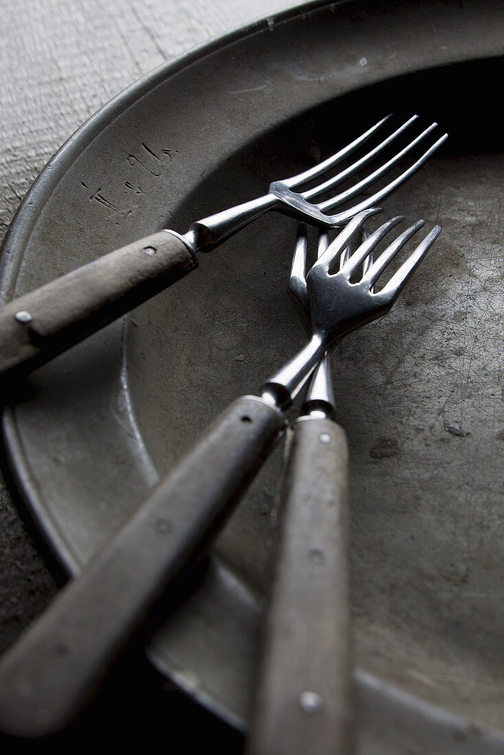 Three old forks on an old plate