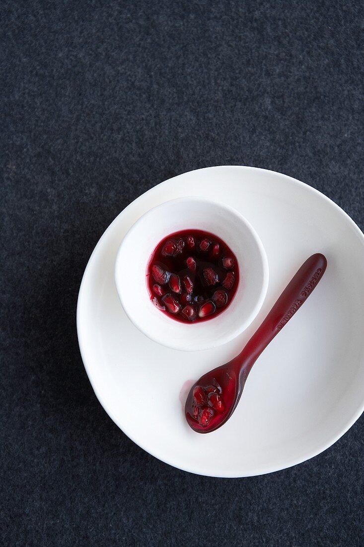 Pomegranate seeds in a bowl and a spoon