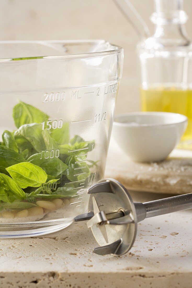 Basil leaves and pine nuts in a measuring cup